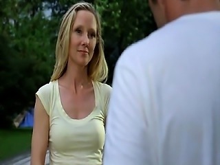 Anne Heche pulling herself up onto a dock beside a lake at
